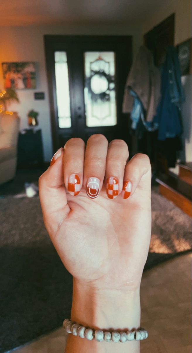 Smiley face nails, fall nails, different on every nail, orange, rust, brown, trending nails, checkerboard, 2022 nails, current trends, fall asthetic, caramel nails Brown Checkered Fall Nails, Fall Smiley Face Nails, Orange Smiley Face Nails, Neutral Smiley Face Nails, How To Checkerboard Nails, Orange Checkerboard Nails, Cute Fall Nails Orange, Checkered Gel Nails Short, Brown Smiley Face Nails