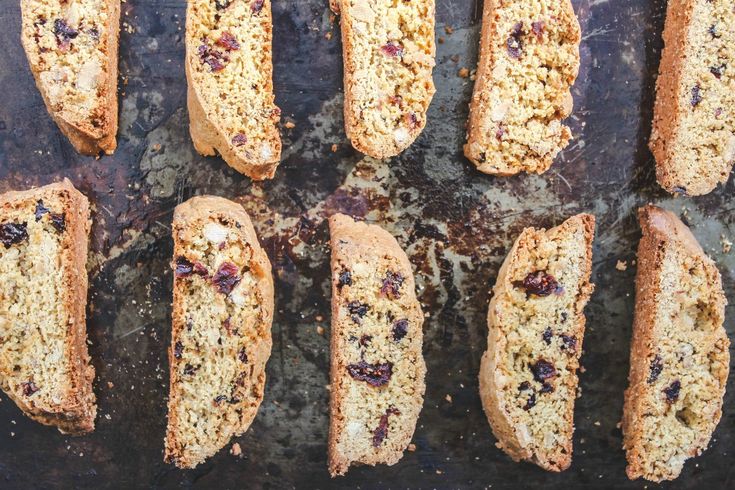 nine pieces of bread with cranberry toppings on a baking sheet, ready to be baked