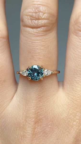 a woman's hand with a blue and white diamond ring on top of it