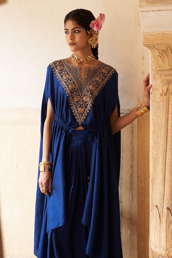 Blue cape with embroidered lotus motifs on front yoke, gathered details on waist and asymmetric hem. Paired with a pleated front skirt. - Aza Fashions Blue Ceremonial Dress With Traditional Drape, Traditional Embroidered Dress With Cape Sleeves, Traditional Indigo Dress For Festive Occasions, Traditional Indigo Dress For Festive Season, Traditional Dresses With Cape Sleeves For Navratri, Traditional Anarkali Set With Intricate Embroidery And Cape Sleeves, Traditional Sharara With Cape Sleeves, Traditional Embroidered Palazzo Set With Cape Sleeves, Ceremonial Blue Lehenga With Traditional Drape