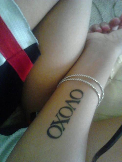 a woman with a tattoo on her arm that says odono and is sitting down