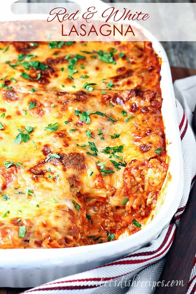 red and white lasagna in a casserole dish with parsley on top