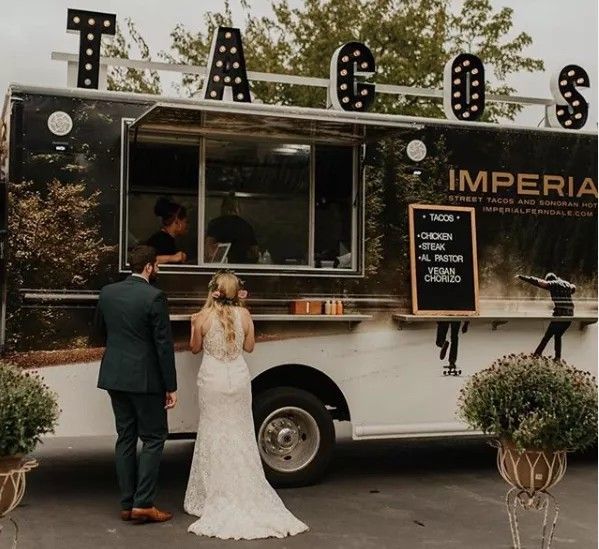 a bride and groom standing in front of a food truck with the word imperia written on it