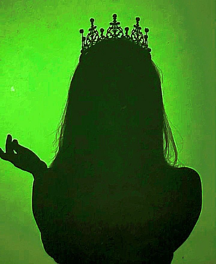 a woman with a crown on her head is silhouetted against a green background,