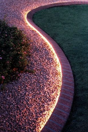 a garden path lit up at night with lights in the grass and flowers on the ground