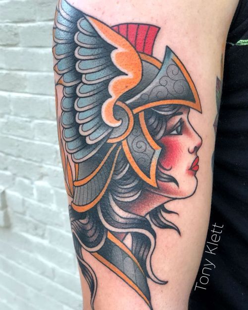 a close up of a person with a tattoo on their arm and head wearing a helmet