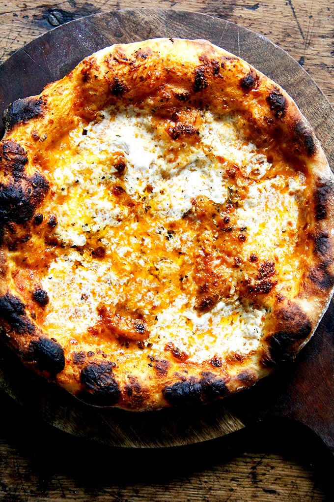 a pizza sitting on top of a wooden cutting board next to a knife and fork