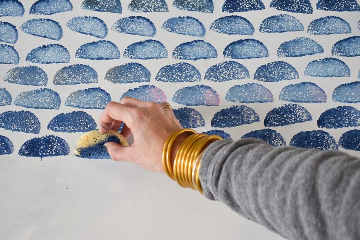 a person is using a sponge to paint the wallpaper with blue and white designs