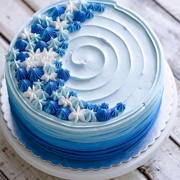 a blue and white cake sitting on top of a wooden table covered in frosting