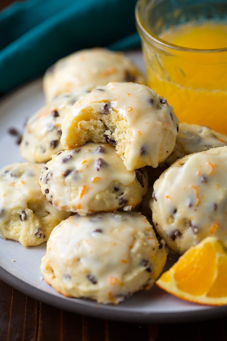 oranges and chocolate chip cookies on a plate next to a glass of orange juice