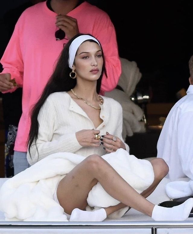 a woman sitting on the back of a boat in a bathrobe with her legs crossed