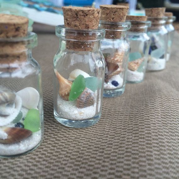 small glass bottles filled with sand and sea shells