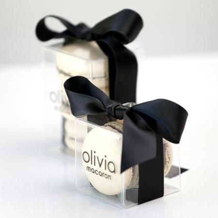 two clear boxes with black bows on the top and bottom are filled with white chocolates