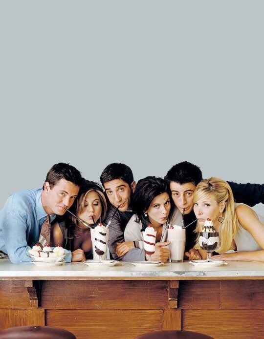 the cast of friends posing for a photo at a table with cups and milkshakes