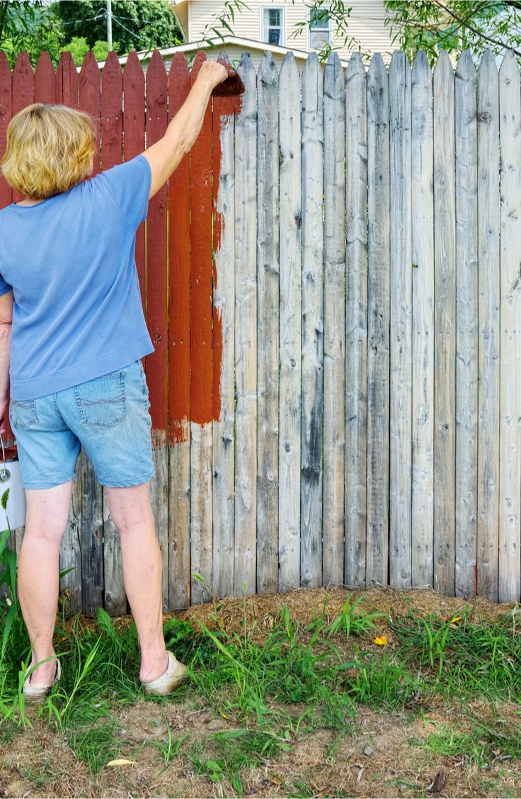 a woman in blue shirt standing next to wooden fence