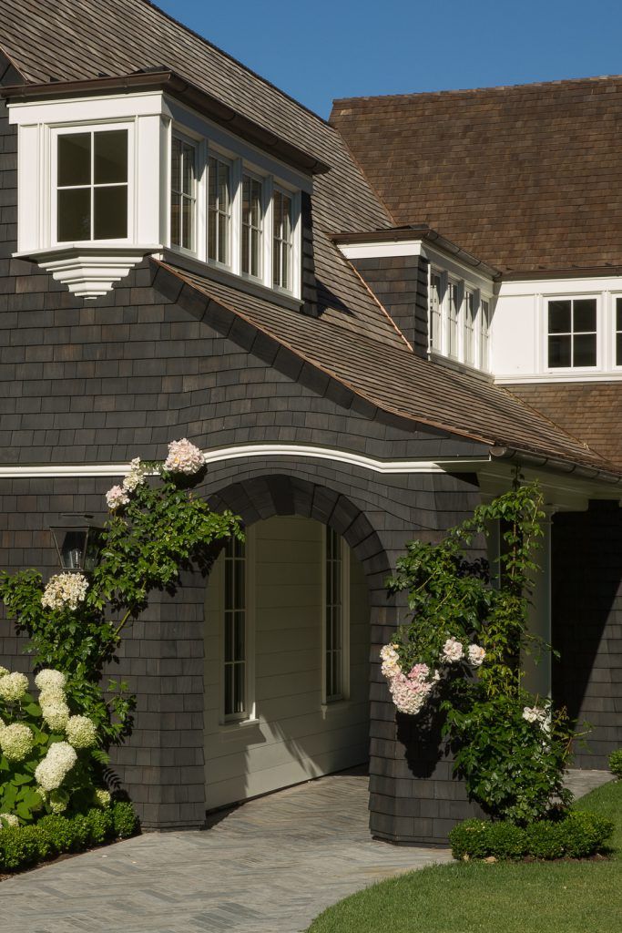 a house with white flowers growing on the front and side of it's windows