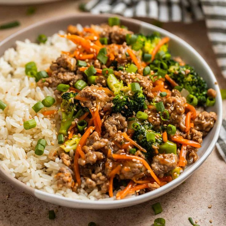 a white bowl filled with rice, meat and veggies