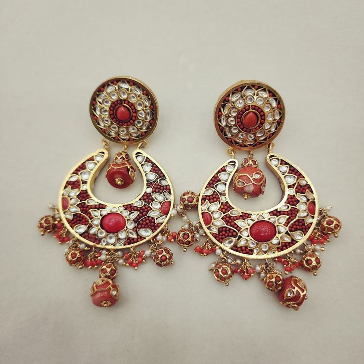 Enhance your look with these elegant Coral Chandbali Earrings. Featuring intricate designs with coral drops, these earrings bring a perfect blend of tradition and sophistication to any outfit. Ideal for festive occasions, they add a vibrant and graceful touch to your ensemble. Length: 3" to 3.5" Material: 24Kt gold foil, lac Stones: Kundans, semi precious corals, semi precious pearls Red Chandbali Jewelry With Dangling Beads, Red Temple Jewelry Chandbalis With Intricate Design, Traditional Hoop Earrings With Intricate Design For Celebration, Chandbali Earrings With Stone Work, Red Chandbali Jhumkas With Intricate Design, Traditional Dangling Beads Earrings For Celebration, Bohemian Earrings With Stone Work For Festive Occasions, Traditional Kundan Hoop Earrings With Intricate Design, Traditional Earrings With Dangling Beads For Celebration