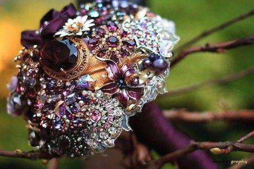 a bridal bouquet sitting on top of a tree branch covered in jewels and pearls