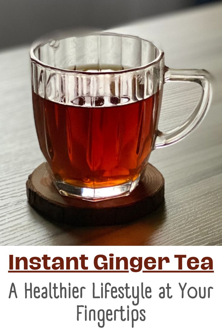 a cup of tea sitting on top of a wooden table next to the words instant ginger tea