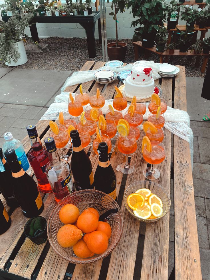 there are many glasses and bottles on the table with oranges next to each other