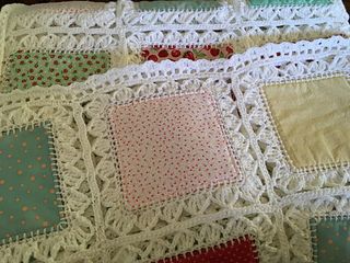 a white crocheted blanket with red, green and yellow polka dots on it