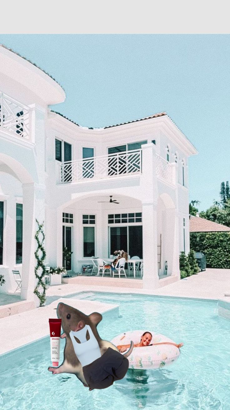 an inflatable elephant floating on top of a pool next to a large white house