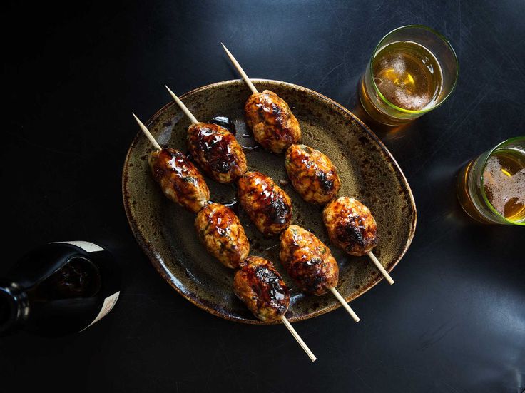 chicken skewers on a plate with two glasses of beer