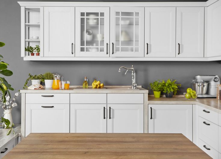 a kitchen with white cabinets and wooden counter tops in front of a green framed wall