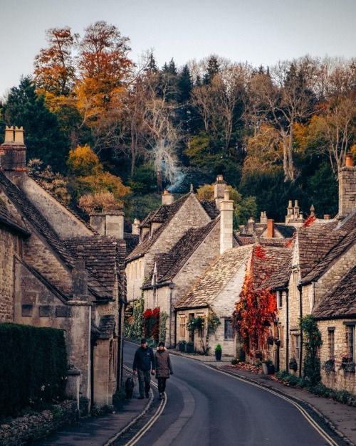 two people are walking down the street in an old village