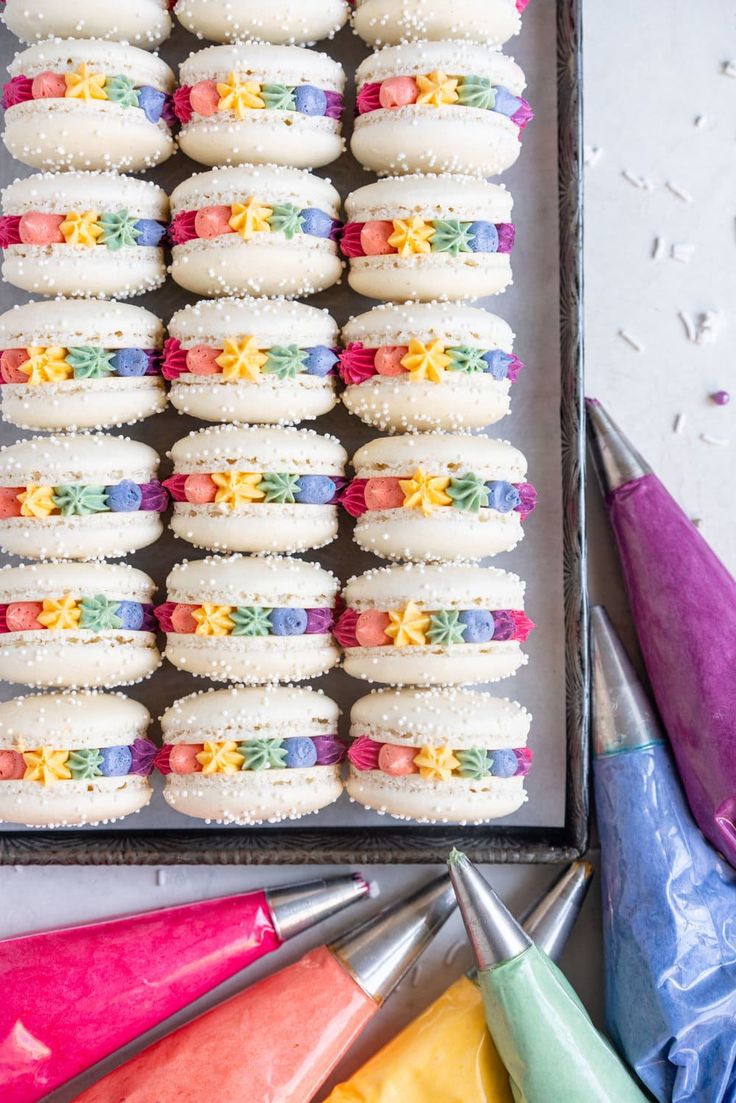 a box filled with lots of colorful cupcakes next to crayon markers