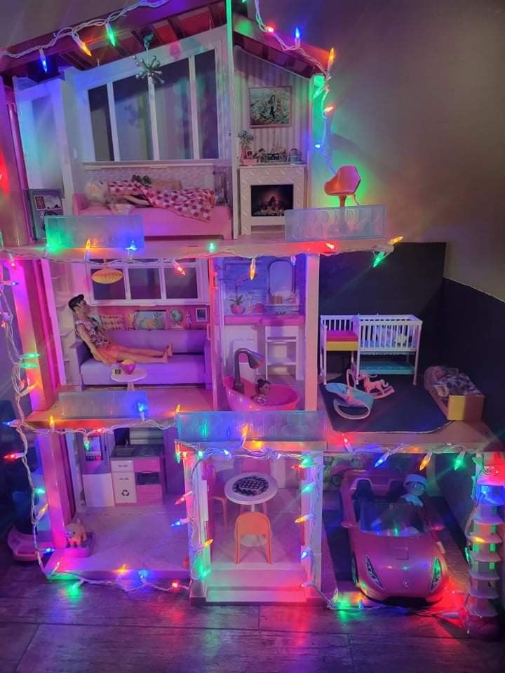 a doll house is lit up with colorful lights and decorations on the walls, along with toys