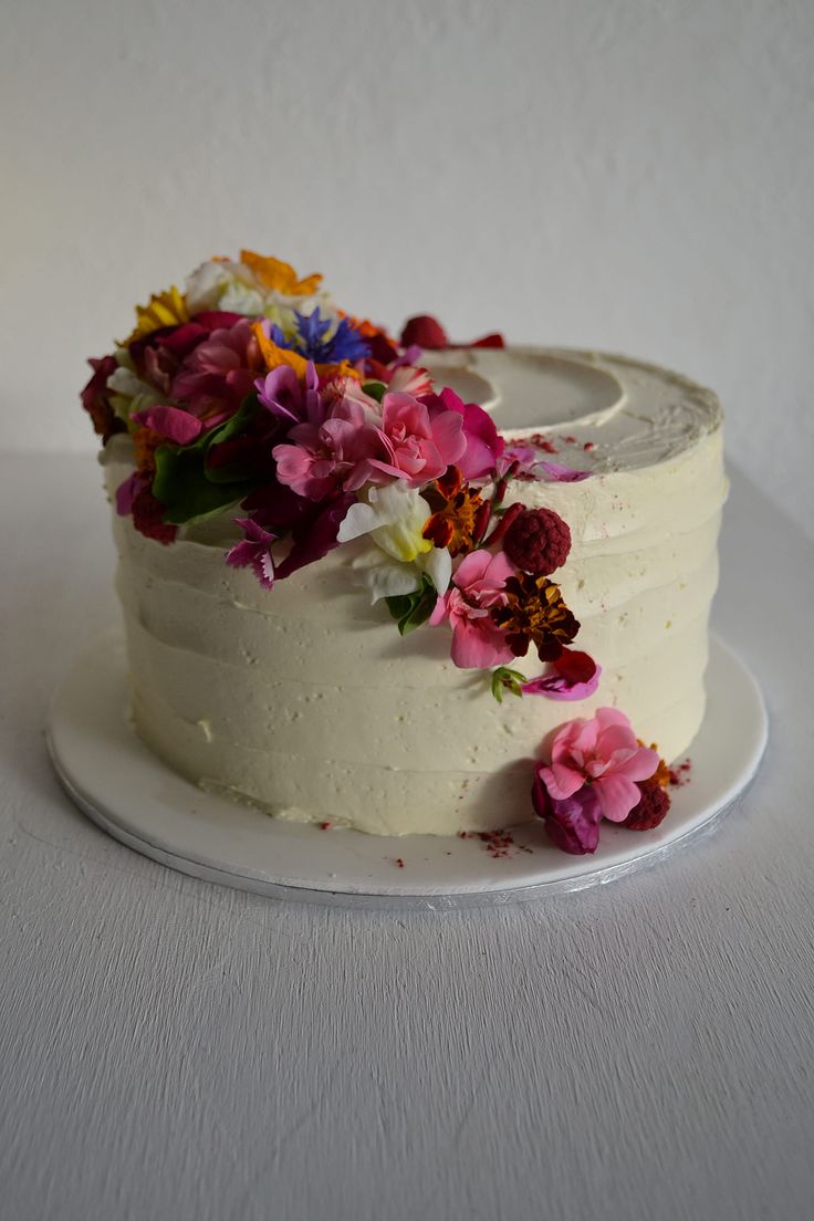 a white cake with flowers on it sitting on a plate