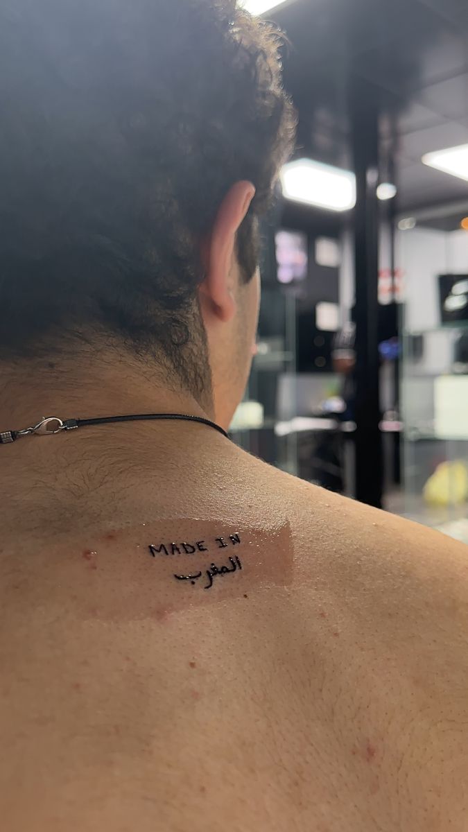 the back of a man's neck with writing on his left shoulder and chest