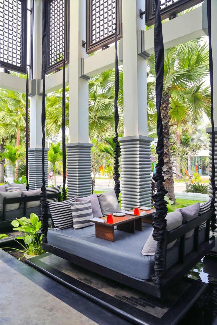 an outdoor living area with couches, tables and palm trees