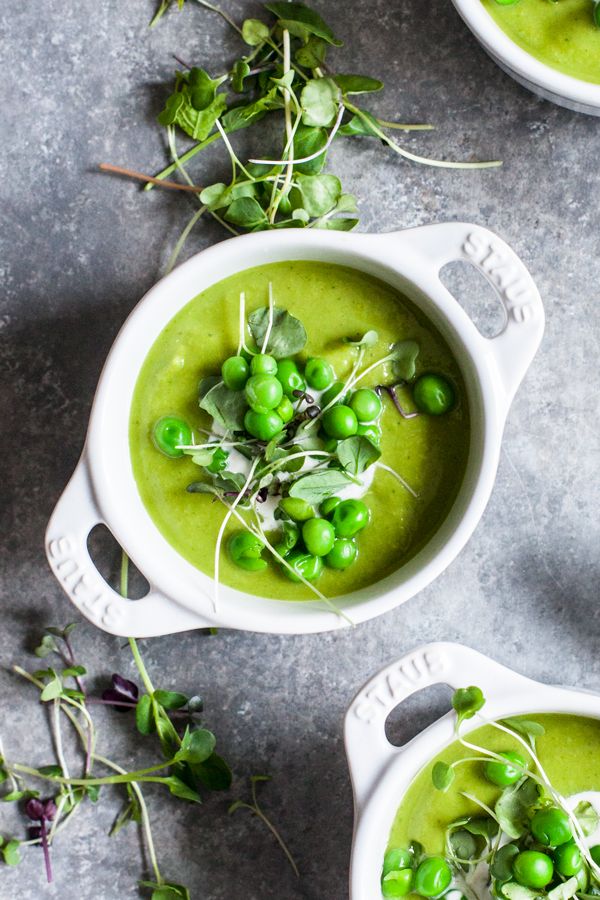 three white bowls filled with green pea soup and garnished with sprouts