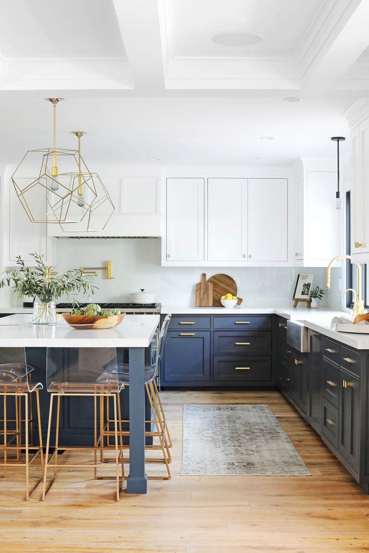 a kitchen with blue cabinets and white counter tops, gold pendant lights above the island