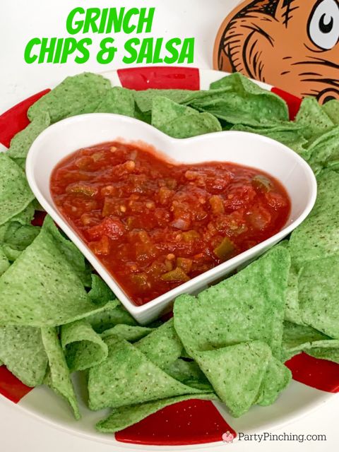 a heart shaped bowl filled with salsa and tortilla chips on top of a plate