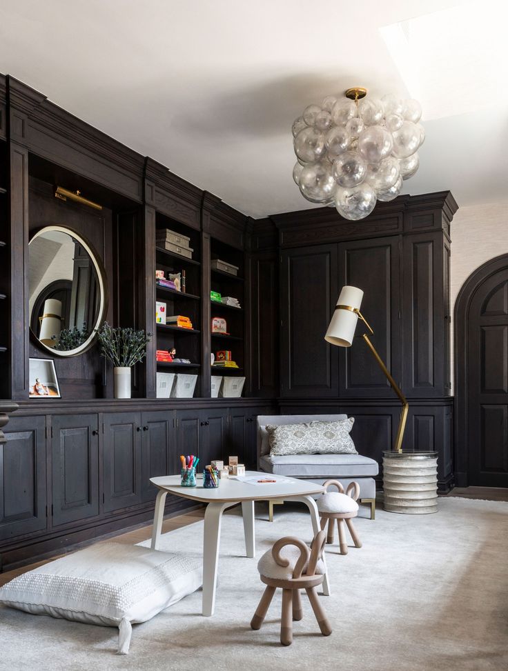 a living room with dark wood paneling and white carpeted flooring on the walls