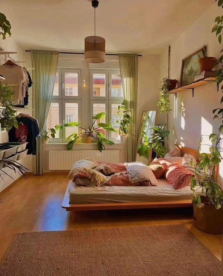 a bedroom with lots of plants in the window sill and a bed on top of a wooden floor