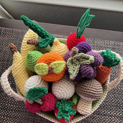 a crocheted basket filled with fruit and vegetables