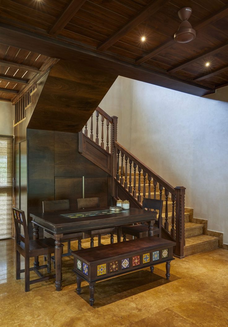 a wooden table sitting under a stair case