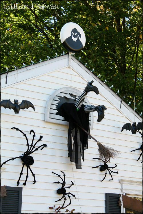 halloween decorations on the side of a white house with bats and spider webs hanging from it's roof