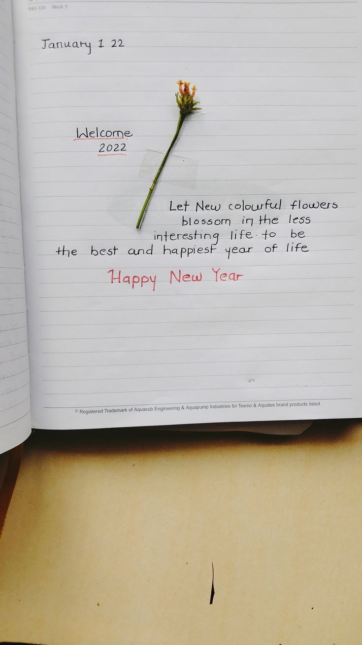 an open notebook with a flower on it and the words happy new year written in cursive writing