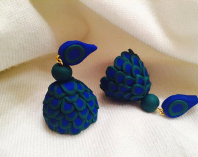 two blue and green earrings sitting on top of a white cloth next to each other