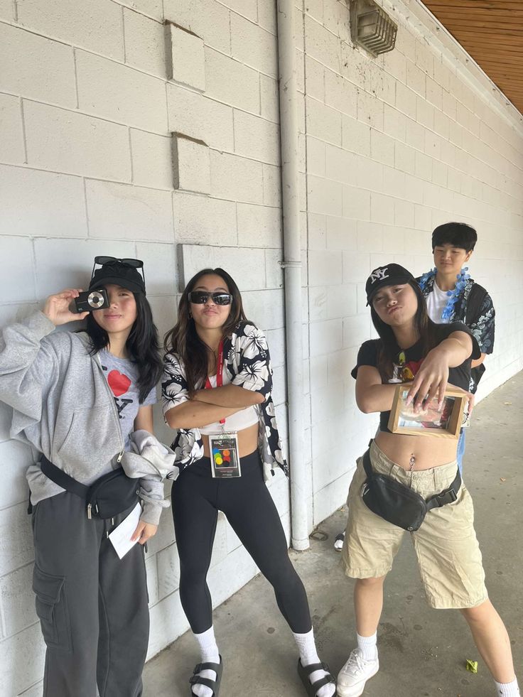 three young people standing next to each other in front of a white wall with their hands on their hipss