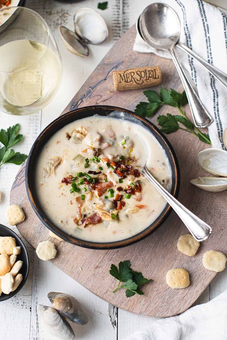 a bowl of soup is sitting on a cutting board with spoons and other food