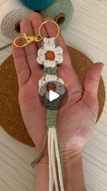 someone is holding their hand with some yarn on it and two crocheted flowers in the middle