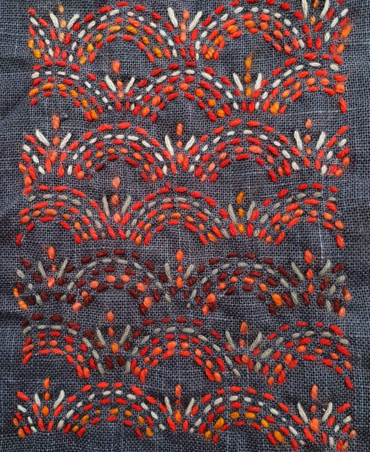 a piece of cloth with red and orange beads on it