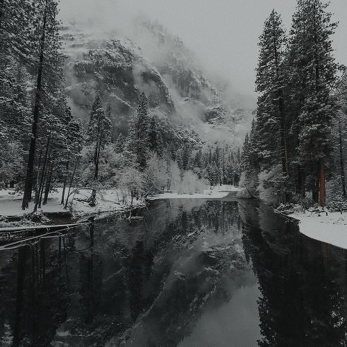 a river surrounded by snow covered mountains and trees